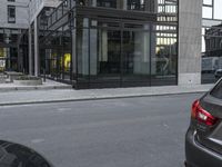 two vehicles are parked on the street next to each other near a building with a glass enclosed door and windows