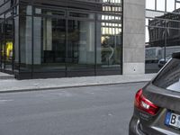 two vehicles are parked on the street next to each other near a building with a glass enclosed door and windows