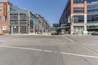 empty city street with buildings and street cars along side of it on clear day, in the middle of winter