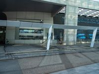 a big building with a glass cover on the front of it is next to a sidewalk