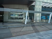 a big building with a glass cover on the front of it is next to a sidewalk