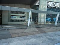 a big building with a glass cover on the front of it is next to a sidewalk