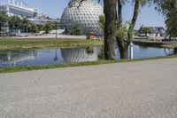 the scene has many buildings with a river behind them and a water fountain next to it