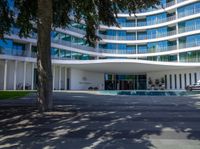 a building with many floors and windows with grass in front of it and the sign welcomes all on