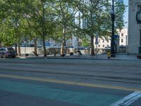 an empty street with buildings and parked cars on the sidewalks and green lanes on the sidewalk