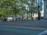 an empty street with buildings and parked cars on the sidewalks and green lanes on the sidewalk