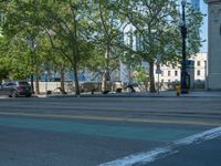 an empty street with buildings and parked cars on the sidewalks and green lanes on the sidewalk