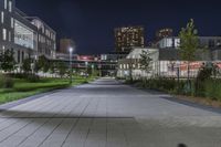 the sidewalk and the grass are illuminated by light fixtures at night, next to an office building