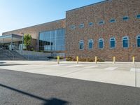 the empty street is lined with stairs leading to a brick building on a sunny day