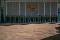 the door and windows of the entrance to the office building with large plants in pots on the wooden walkway