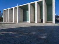 an artistic looking building made out of many pillars and columns, including a windowed glass wall