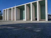 an artistic looking building made out of many pillars and columns, including a windowed glass wall