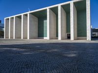 an artistic looking building made out of many pillars and columns, including a windowed glass wall