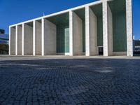 an artistic looking building made out of many pillars and columns, including a windowed glass wall