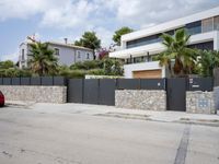 a street is shown with the fence closed down in front of the building and palm trees on either side of it