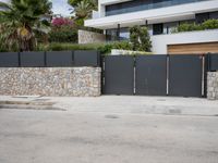 a street is shown with the fence closed down in front of the building and palm trees on either side of it