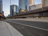 the side view of an empty road with traffic signals in a city skyline area next to highway