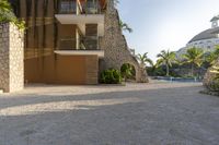 this photo shows a house with a driveway of stones and trees in front of it