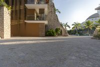 this photo shows a house with a driveway of stones and trees in front of it