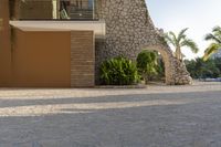 this photo shows a house with a driveway of stones and trees in front of it