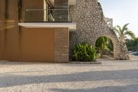 this photo shows a house with a driveway of stones and trees in front of it