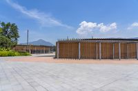 a building with some poles and brick walkway outside of it, near a grass field