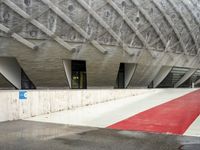 the entrance to a building in the city, with red paint on the ground and concrete wall, and white trims