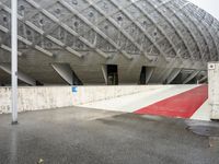 the entrance to a building in the city, with red paint on the ground and concrete wall, and white trims