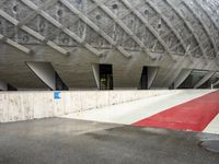 the entrance to a building in the city, with red paint on the ground and concrete wall, and white trims