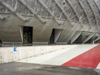 the entrance to a building in the city, with red paint on the ground and concrete wall, and white trims