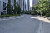 a car driving down an empty street lined with tall buildings and trees in the background