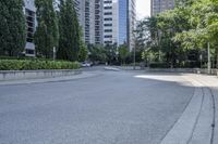 a car driving down an empty street lined with tall buildings and trees in the background