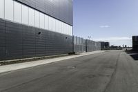 an empty street next to a very large building next to a highway area with cars going by