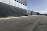 an empty street next to a very large building next to a highway area with cars going by