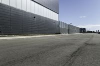 an empty street next to a very large building next to a highway area with cars going by