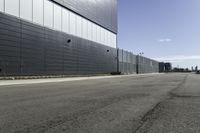 an empty street next to a very large building next to a highway area with cars going by