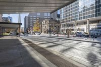 a view of buildings from the sidewalk in front of it, with a bus, cars, and orange cones