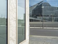 the building is reflected in the windows of the building beside it on the road in front