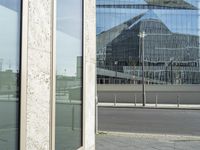 the building is reflected in the windows of the building beside it on the road in front