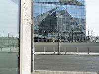 the building is reflected in the windows of the building beside it on the road in front