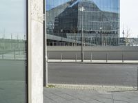 the building is reflected in the windows of the building beside it on the road in front