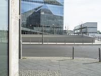 the building is reflected in the windows of the building beside it on the road in front