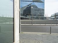 the building is reflected in the windows of the building beside it on the road in front