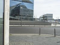 the building is reflected in the windows of the building beside it on the road in front