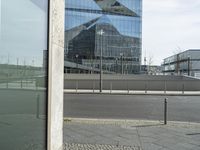 the building is reflected in the windows of the building beside it on the road in front