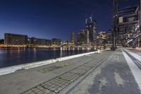 the concrete walkway on the shore of the city is empty and full of people at night