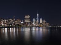 a city skyline with skyscrapers reflecting in the water at night, with boats out