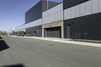 an industrial building sitting on the side of the road in a city street, with asphalt and concrete floor