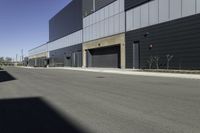 an industrial building sitting on the side of the road in a city street, with asphalt and concrete floor