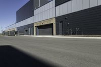 an industrial building sitting on the side of the road in a city street, with asphalt and concrete floor